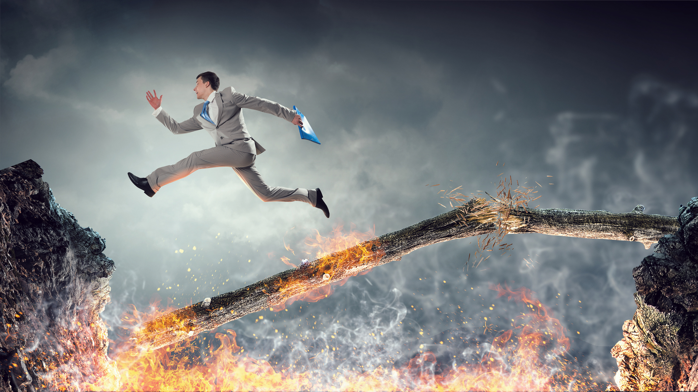 Businessman jumping over burning log.